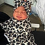 baby, infant, sleeping, leopard_print, headband, swaddle, clothing, portrait, indoor, person, newborn, cute, face, peaceful, soft_lighting, fabric, closeup, human, resting, cozy