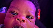 Noah is registered to the contest to win money with this photo: baby, close_up, clothing, curly_hair, cute, expression, eyes, face, head, indoor, infant, messy_mouth, mouth, newborn, nostrils, person, portrait, purple_lighting, skin, young_child