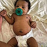 baby, pacifier, diaper, curly_hair, infant, lying_down, blanket, skin, cute, child, sleepwear, indoors, newborn, resting, person, soft, toddler, face, hand, foot