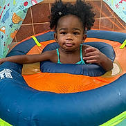 Melody is registered to the contest to win money with this photo: child, toddler, inflatable, pool, water, float, swimming, toy, dinosaur, canopy, blue, orange, green, hair_bow, curly_hair, face, summer, outdoor, water_toy, baby_swimming