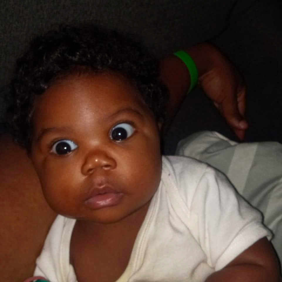 Anastasia joined the competition — help win amazing prizes! arm, baby, child, closeup, clothing, curious, cute, dark_background, expression, face, hand, holding, indoors, infant, pacifier, person, portrait, skin, white_shirt, wide_eyes