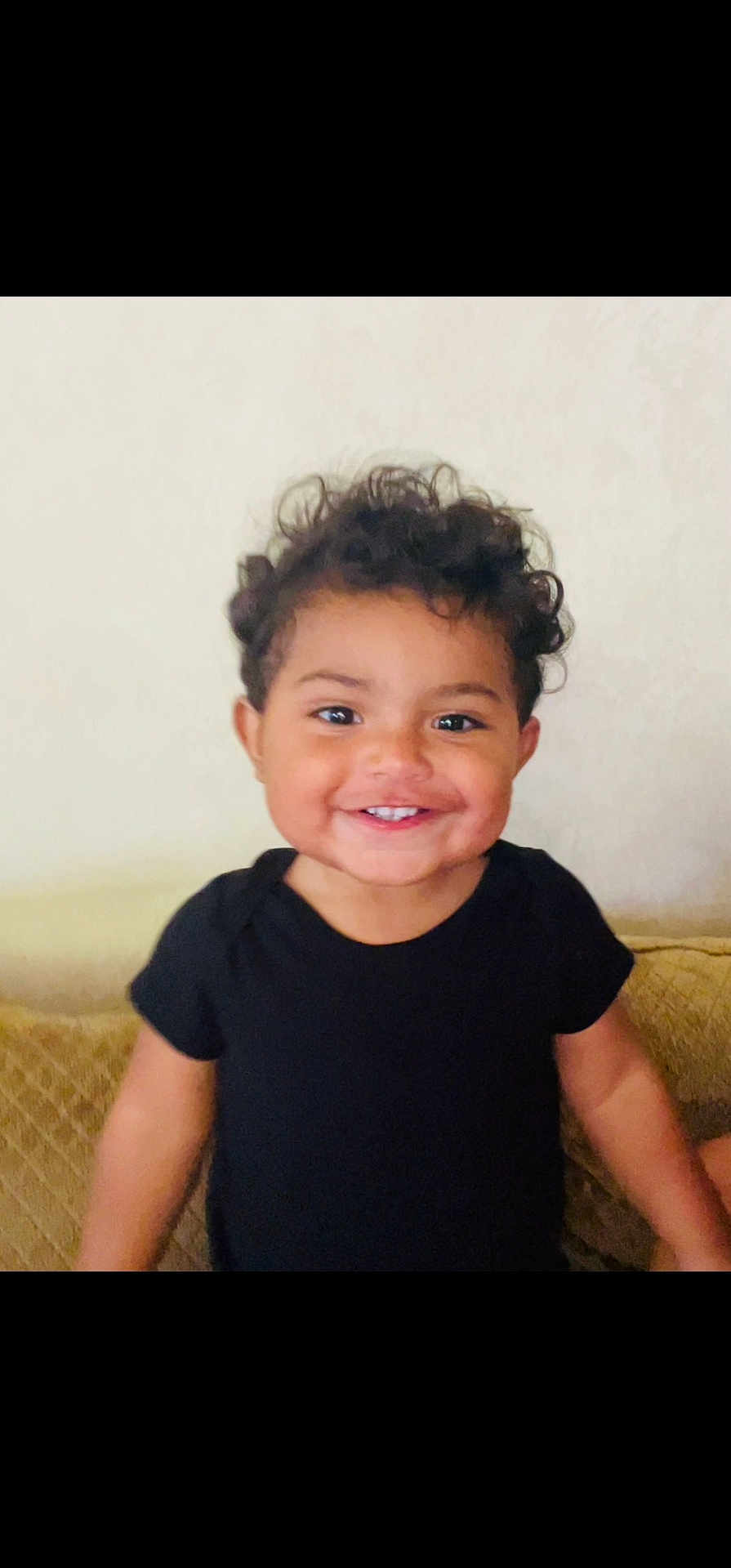 Dillan joined the competition — help win amazing prizes! toddler, child, smiling, curly_hair, black_shirt, happy, standing, indoors, face, portrait, cute, young_child, person, skin, human, hair, eyes, mouth, expression, background