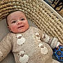 baby, child, smiling, sweater, sheep_pattern, toy, basket, woven, indoor, cozy, cute, person, face, happy, clothing, hand, blue_toy, striped_cushion, furniture, portrait