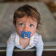 Mattéo participe au concours pour gagner de l'argent avec cette photo : toddler, child, pacifier, blue_pacifier, curious, wide_eyes, hands, wooden_floor, indoor, soft_focus, blurry_background, striped_clothing, baby, cute, portrait, crawling, young_child, innocent, hair, looking_up