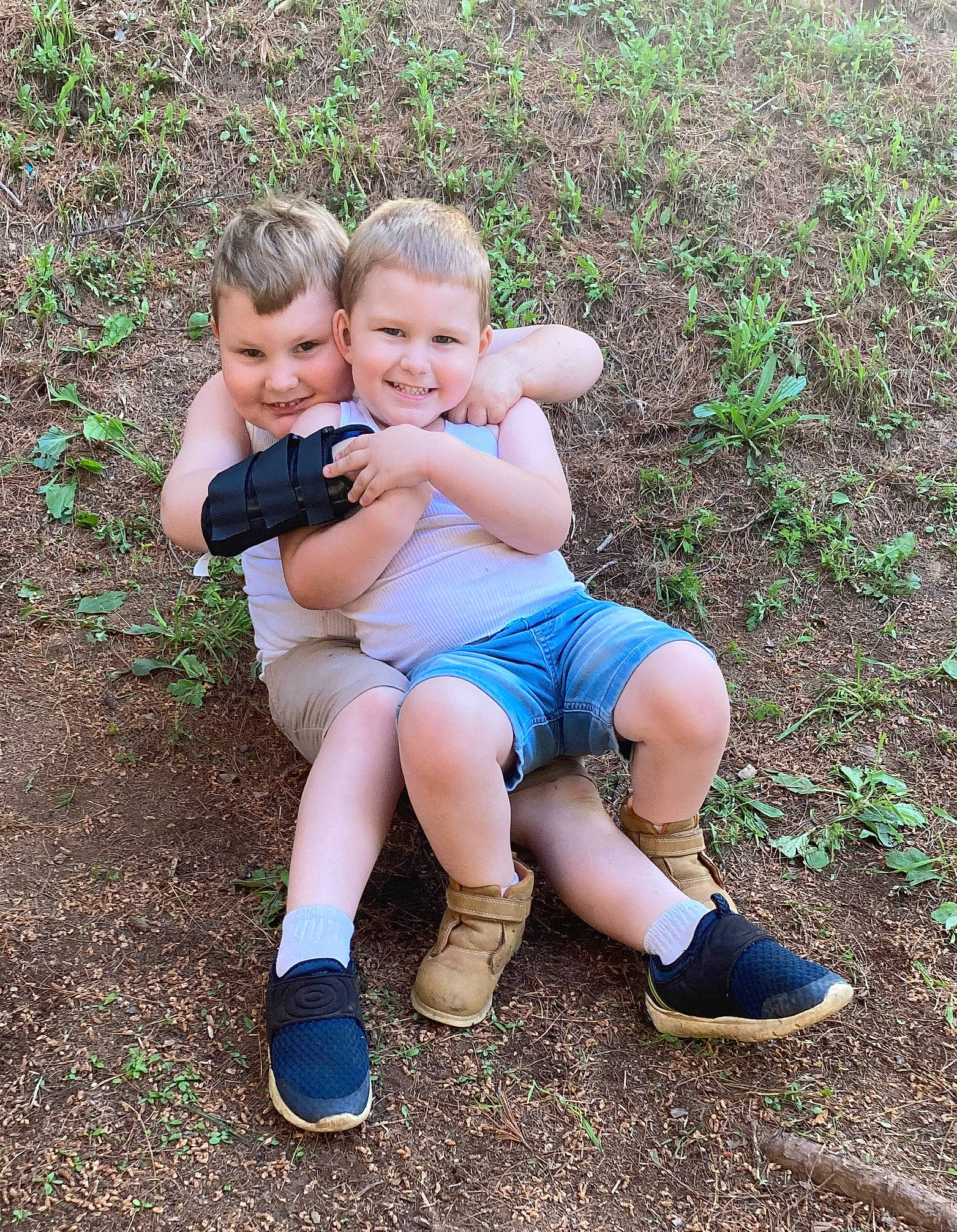 Weston is registered to the contest to win money with this photo: baby_toddler_clothing, child, face, finger, foot, fun, gesture, grass, grass_family, happy, joy, leg, leisure, people_in_nature, person, plant, shoe, sitting, smile, sneakers