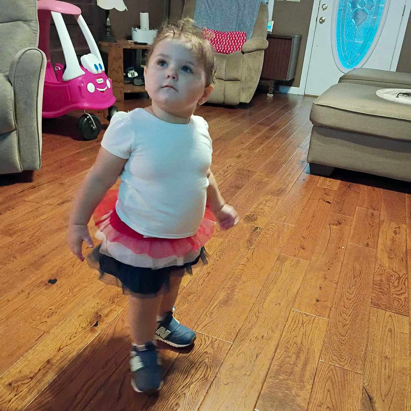 Tyranny joined the competition — help win amazing prizes! toddler, child, living_room, wooden_floor, tutu_skirt, sneakers, toy_car, furniture, window, door, lamp, curious, indoor, person, home, decor, cushion, table, carpet, blanket