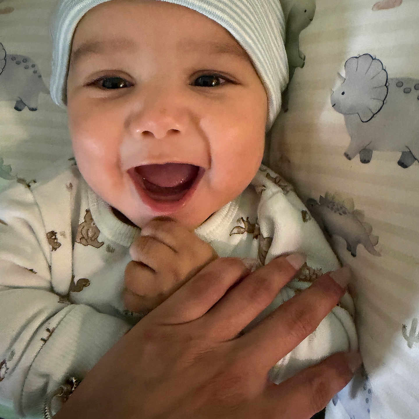 Yaid Santiago is registered to the contest to win money with this photo: baby, bedding, child, closeup, cute, dinosaur_pattern, expression, face, hand, happy, hat, holding, indoor, infant, joy, pajamas, person, sleepwear, smiling, striped_hat