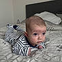 baby, infant, striped_pajamas, bed, bedding, blanket, face, head, hands, blue_eyes, room, pillow, sleepwear, person, lying_down, curious, indoors, young_child, bedroom, soft_light