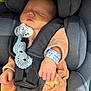 baby, newborn, sleeping, car_seat, pacifier, baby_clothing, wristband, handwritten, infant, child, baby_toy, wooden_toy, safety_harness, gray, peach, cute, peaceful, indoors, portrait, closeup