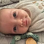 baby, infant, face, blue_eyes, blanket, quilted, onesie, lying_down, close_up, skin, head, cute, soft_texture, knitted_toy, child, newborn, smile, portrait, indoor, resting