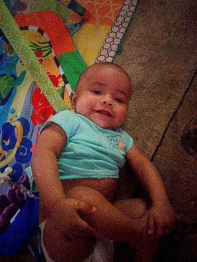 Grayson is registered to the contest to win money with this photo: baby, baby_toddler_clothing, chair, cheek, chest, child, chin, finger, flooring, fun, happy, human_leg, iris, pattern, person, skin, smile, thigh, toddler, trunk