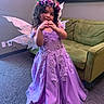 Emelina joined the competition — help win amazing prizes! child, girl, purple_dress, fairy_wings, flower_crown, heart_hand_sign, smiling, curly_hair, indoor, carpet, couch, wall_art, portrait, costume, happy, home, furniture, decor, person, playful