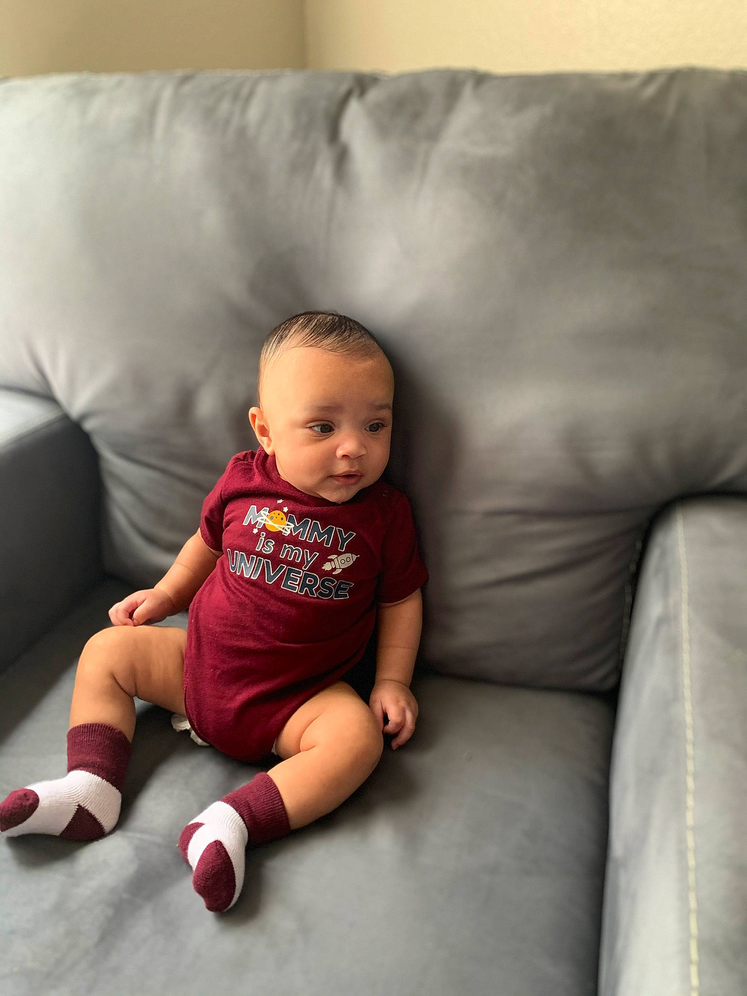 Hector is registered to the contest to win money with this photo: baby, cheek, child, couch, electronic_device, face, footwear, fun, furniture, head, leg, people, person, pink, room, shoe, sitting, skin, smile, toddler