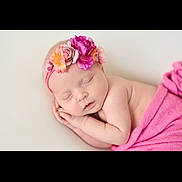 Rose is registered to the contest to win money with this photo: baby, newborn, sleeping, flower_headband, pink_blanket, infant, peaceful, portrait, cute, soft_lighting, closeup, skin, child, adorable, resting, headband, wrapped, peace, tender, young