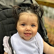 Lydia joined the competition — help win amazing prizes! baby, bib, child, clothing, cute, eyes, face, hair, happy, infant, mouth, outdoor, person, pigtails, portrait, seat, skin, smiling, stroller, young_child