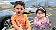 Lydia is registered to the contest to win money with this photo: baby, boy, car, casual_clothing, child, children, cute, daytime, face, girl, hands, headband, orange_shirt, outdoor, parking_lot, person, purple_outfit, shopping_cart, smiling, toddler