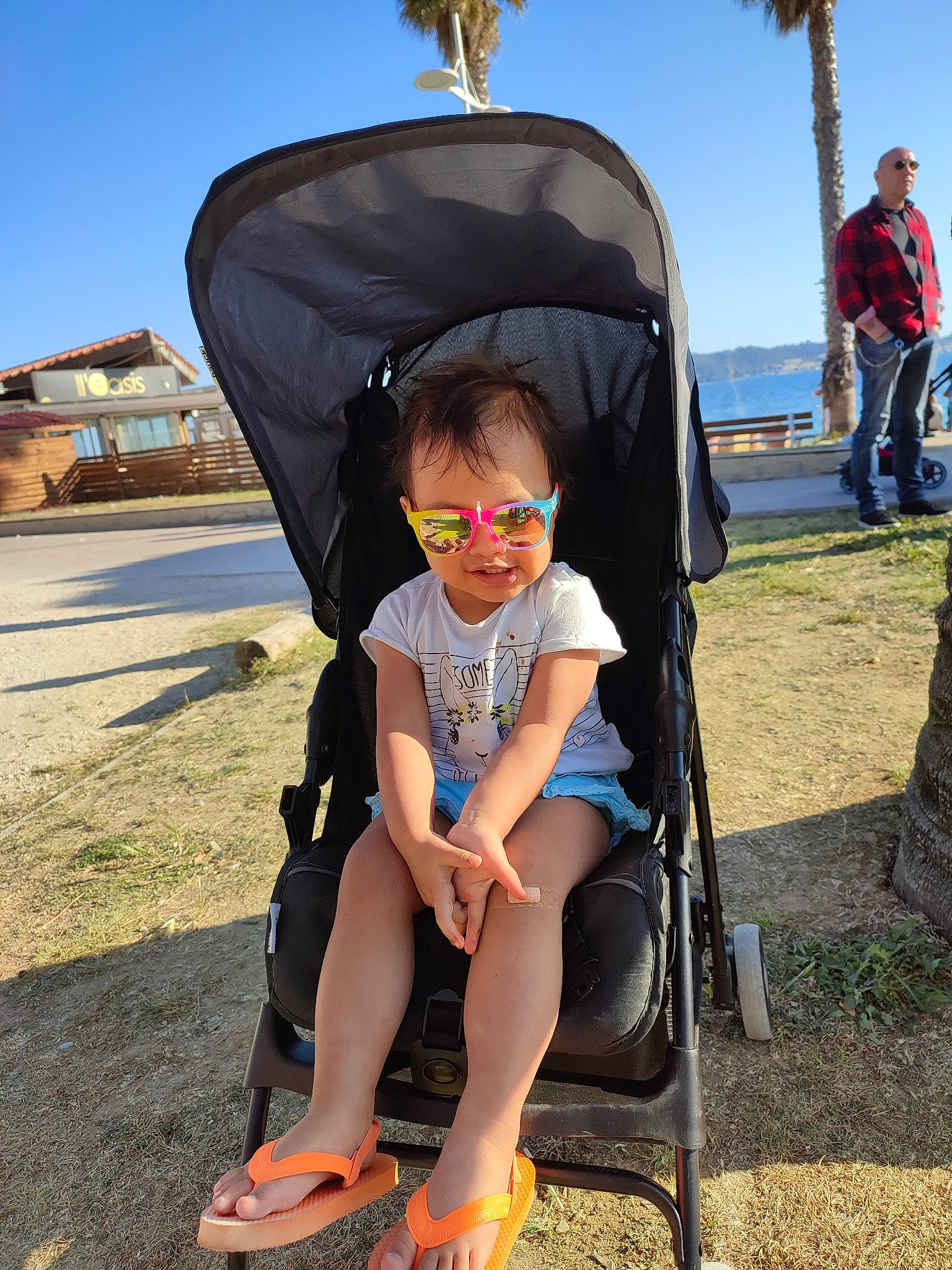 Hope participe au concours pour gagner de l'argent avec cette photo : arecales, baby_carriage, eyewear, fun, goggles, grass, leisure, palm_tree, person, personal_protective_equipment, photograph, recreation, shade, sitting, sky, snapshot, summer, toddler, travel, tree