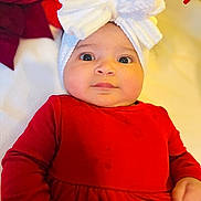 Katalyna is registered to the contest to win money with this photo: baby, infant, child, red_clothing, white_bow, headwear, face, eyes, hand, portrait, indoor, soft_fabric, blanket, cute, expression, person, closeup, newborn, holiday, cozy