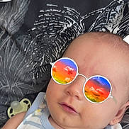 Djamal participe au concours pour gagner de l'argent avec cette photo : baby, infant, face, sunglasses, digital_filter, pacifier, striped_clothing, lying_down, blanket, pattern, cute, child, portrait, head, skin, expression, calm, accessory, colorful, closeup