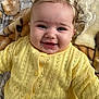 baby, infant, smiling, yellow_sweater, bow, hair, blanket, closeup, portrait, blue_eyes, rosy_cheeks, buttoned_cardigan, knitted, lying_down, cozy, adorable, child, face, eyelashes, happy