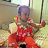 baby, toddler, child, orange_clothing, bows, bed, window, natural_light, indoor, playing, accessories, foot, hand, curious, portrait, person, room, blanket, fabric, candid