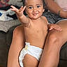 toddler, child, diaper, smile, happy, indoor, couch, legs, person, skin, hair, earrings, hand, face, living_room, pillow, casual, expression, playful, seated
