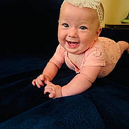 Angelina is registered to the contest to win money with this photo: baby, infant, smiling, headband, bow, pink_clothing, blanket, blue_blanket, cute, happy, child, portrait, indoors, toddler, face, hands, lying_down, young_child, expression, skin