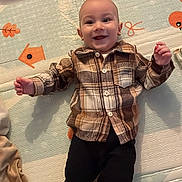 Mârin a rejoint le concours — aidez-le/la à gagner de superbes lots ! baby, smiling, plaid_shirt, pants, play_mat, infant, lying_down, happy, child, footwear, indoor, cute, face, person, young, clothing, pattern, baby_toys, colorful, background
