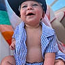 Axton is registered to the contest to win money with this photo: baby, baby_face, baby_skin, blue_sky, cheerful, child, clothing, cute, happy, hat, headwear, infant, outdoor, person, portrait, relaxed, sitting, smiling, striped_clothing, sunlight