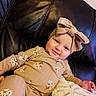 baby, infant, child, smiling, headband, bow, beige_clothing, floral_pattern, couch, leather, blanket, soft_texture, portrait, indoors, cute, happy, person, toddler, sitting, cozy