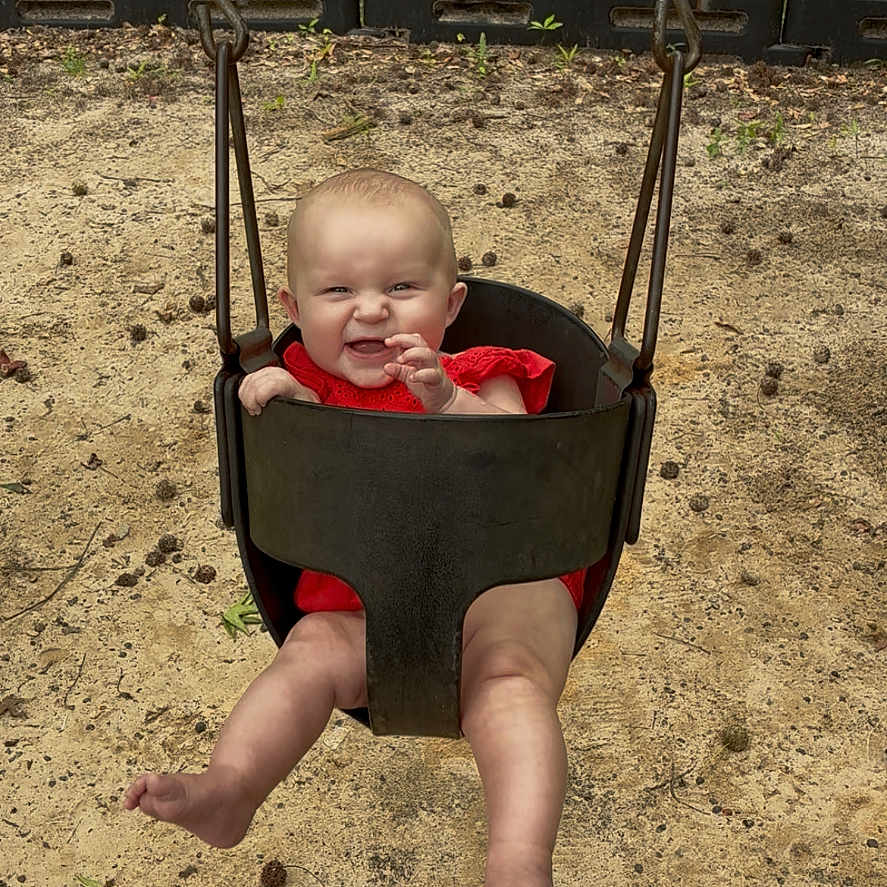 Oaklynn joined the competition — help win amazing prizes! baby, child, swing, playground, sand, grass, tree, red_clothing, smiling, happy, outdoor, sunlight, legs, feet, seat, chains, nature, infant, fun, park