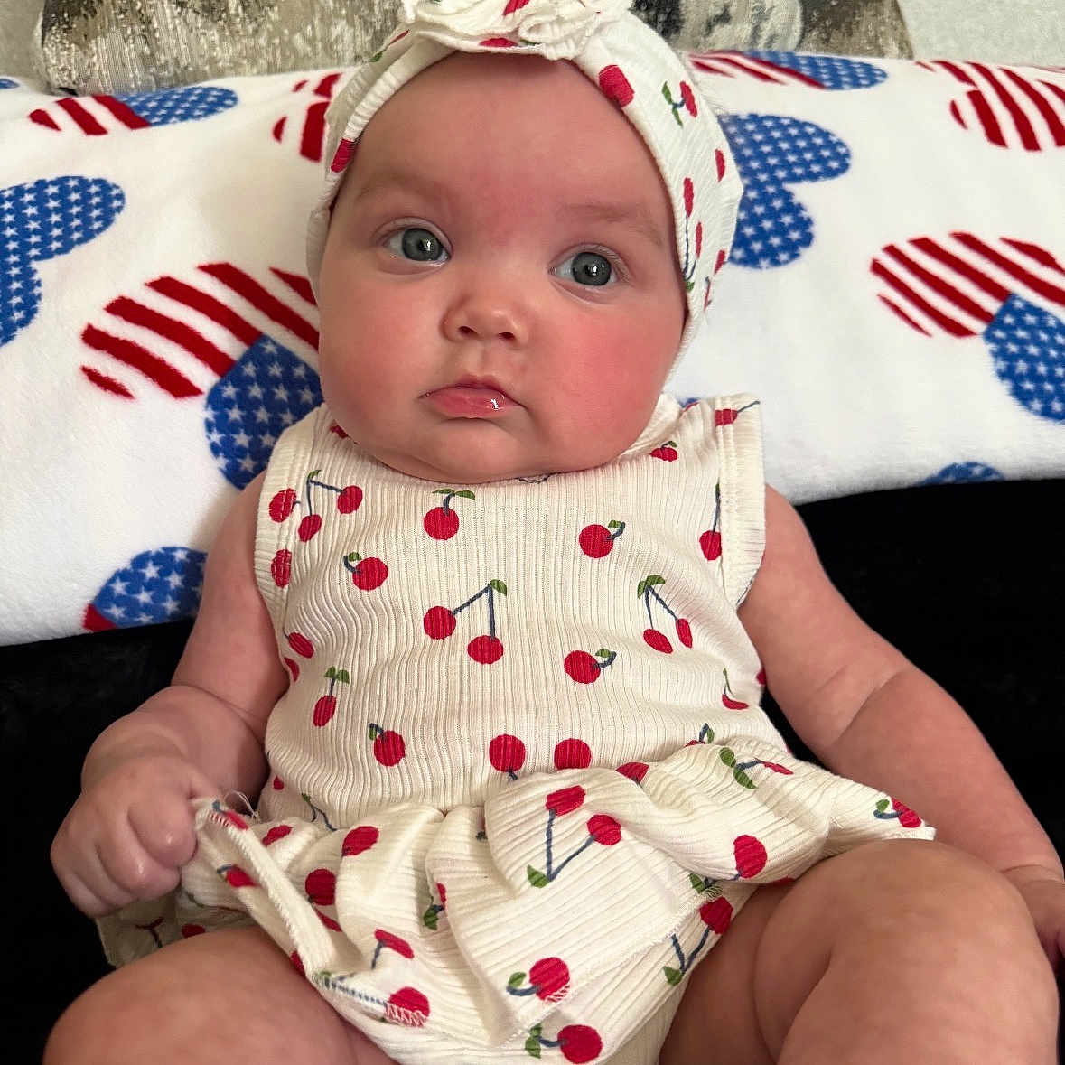 Ariel is registered to the contest to win money with this photo: baby, infant, child, face, headband, clothing, pattern, cherry, sitting, blanket, heart_pattern, cute, portrait, skin, expression, indoors, person, fashion, headwear, eyes
