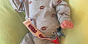 Kayson is registered to the contest to win money with this photo: 49ers, baby, blanket, booties, child, clothing, comfortable, cute, football_print, footwear, gray_outfit, headwear, indoor, infant, pacifier, person, red_hat, resting, smiling, soft_pillow