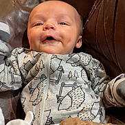 Kayson joined the competition — help win amazing prizes! baby, baby_garment, blanket, brown_leather, child, clothing, cozy, cute, dimples, face, happy, hedgehog_pattern, indoor, infant, onesie, portrait, resting, seat, smiling, young