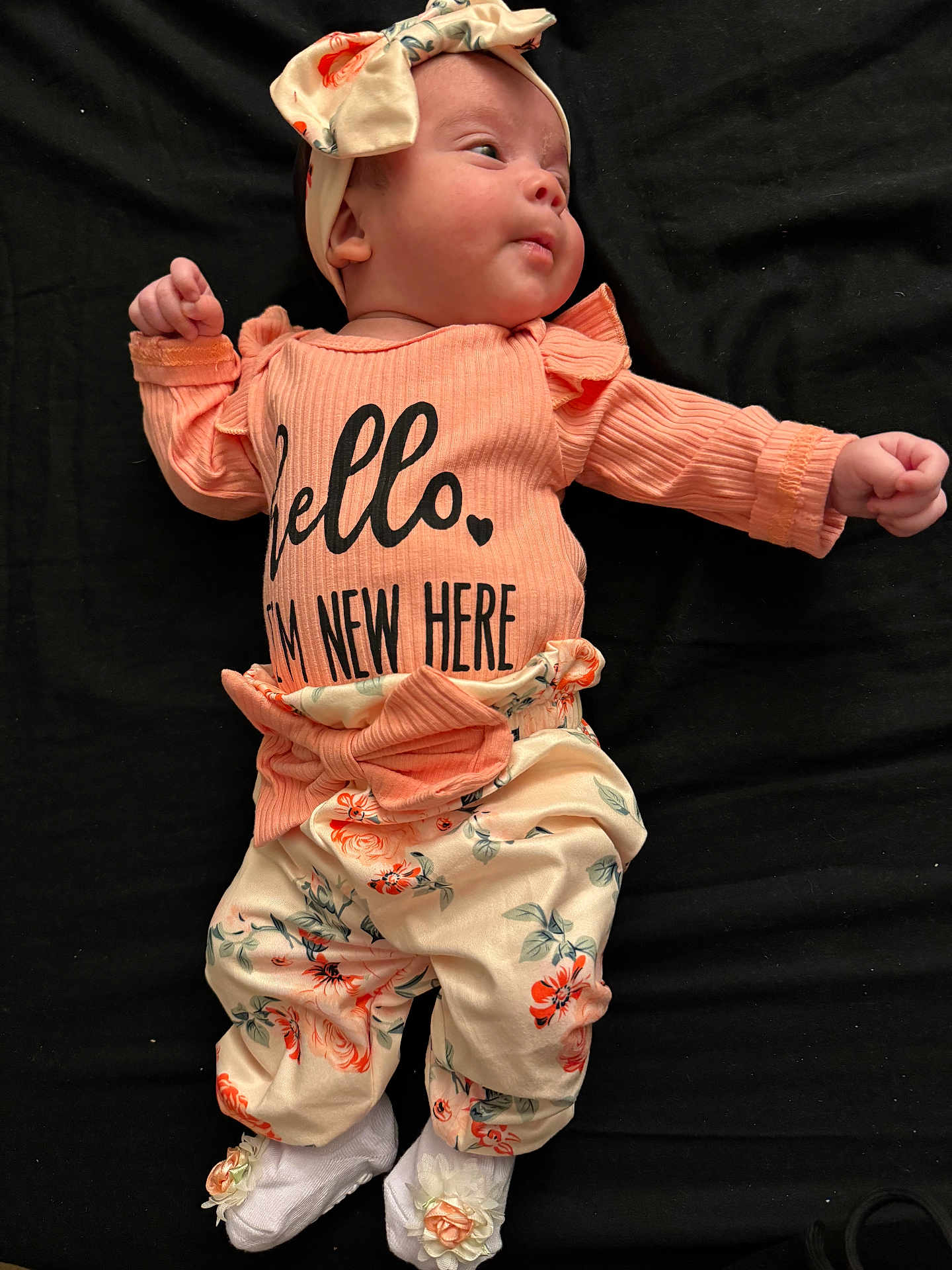 Zulnelys joined the competition — help win amazing prizes! baby, baby_girl, black_background, bow, clothing, cute, expression, face, floral, flower_decoration, headband, infant, lying_down, newborn, pants, peach, portrait, shirt, small_hands, white_socks