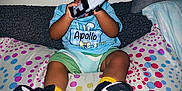 Apollo is registered to the contest to win money with this photo: baby, bedspread, blue_hat, blue_shirt, child, controller, couch, curious, cute, easter, footwear, indoor, person, pillow, polka_dots, sitting, sneakers, toddler, toy, yellow_socks