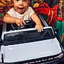 baby, child, toy_car, ford_bronco, steering_wheel, christmas, gifts, fireplace, holiday, smiling, indoor, festive, happy, present, celebration, cute, portrait, seasonal, decorations, joyful