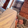 Finlay is registered to the contest to win money with this photo: baby, blanket, child, clothing, couch, cozy, face, furniture, hand, head, home, indoor, pacifier, person, phone, pillow, plaid, relaxation, sitting, wooden_wall