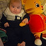 Dawson is registered to the contest to win money with this photo: baby, infant, stuffed_toy, tiger, plush, bed, pillow, clothing, indoors, child, cute, smile, toy, red, yellow, black, white, person, relaxing, home