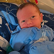 Maverick is registered to the contest to win money with this photo: baby, infant, blue_pajamas, blanket, pacifier, face, newborn, cute, sleepwear, resting, indoors, child, person, soft, cozy, closeup, portrait, comfort, young, patterned