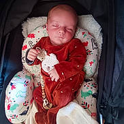 Ellias participe au concours pour gagner de l'argent avec cette photo : baby, infant, sleeping, onesie, bear_design, pacifier, stroller, blanket, cushion, dinosaur_pattern, child, cozy, cute, resting, indoors, peaceful, soft, comfort, wearing, portrait