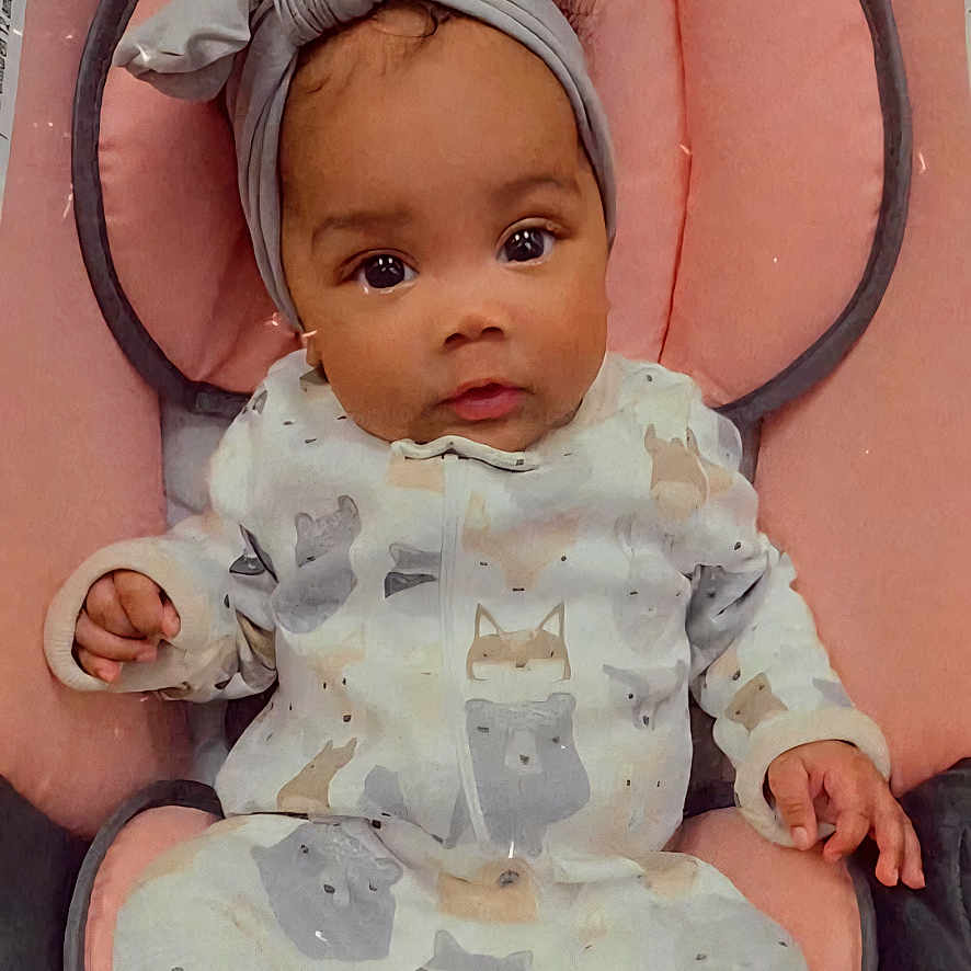 Delilah joined the competition — help win amazing prizes! baby, bodypart, bonnet, cap, chair, clothing, couch, cushion, dress, face, furniture, hat, head, homedecor, newborn, person, photography, portrait, sitting, toy