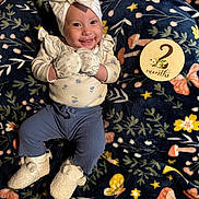 Azariah is registered to the contest to win money with this photo: baby, smiling, mittens, headband, bow, milestone_card, blanket, floral_pattern, pants, booties, infant, cute, lying_down, happy, indoors, soft_texture, child, clothing, person, portrait