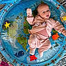 baby, infant, child, portrait, smiling, lying_down, play_mat, inflatable, ocean_theme, sea_animals, colorful, pink_clothing, onesie, socks, indoor, textured_background, toy, playtime, happy, photography