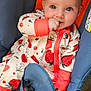 baby, infant, blue_eyes, onesie, strawberry_pattern, orange_cuffs, baby_chair, blue_fabric, carpet, hand, foot, cute, child, seated, indoor, soft_lighting, comfort, playful, looking_at_camera, skin