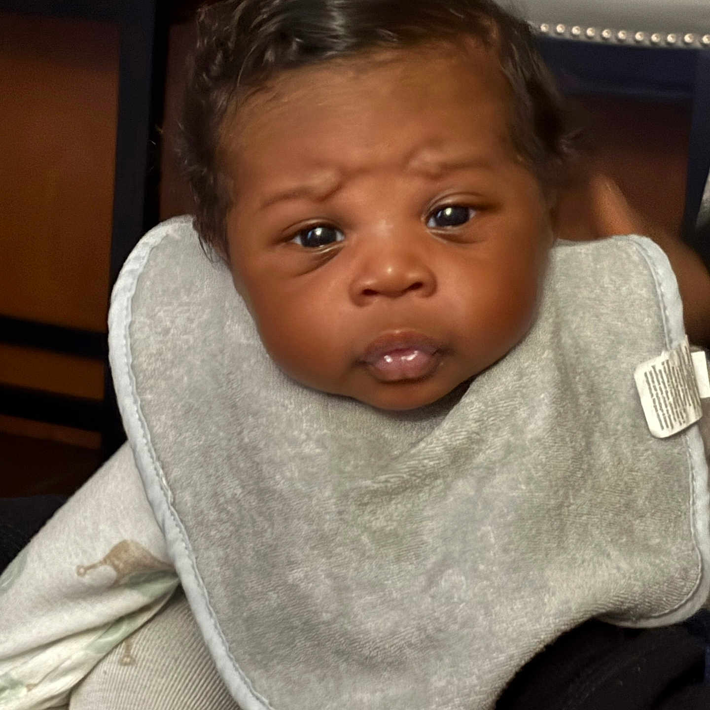 Khyze is registered to the contest to win money with this photo: baby, bib, black_hair, child, closeup, clothing, comfortable, curious_expression, cute, face, human, indoor, infant, newborn, person, portrait, sitting, skin, soft_lighting, young