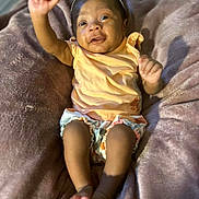 Yahari is registered to the contest to win money with this photo: baby, infant, child, smiling, headband, orange_clothing, blanket, soft_texture, happy, raised_arm, bare_feet, cute, lying_down, indoors, portrait, person, skin, toddler, small_person, cozy
