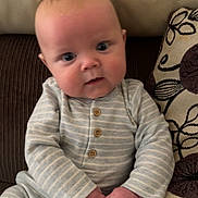 Hugo joined the competition — help win amazing prizes! baby, infant, child, onesie, striped_clothing, couch, pillow, patterned_pillow, hand, face, blue_eyes, seated, indoor, cozy, curious, small_hands, soft_lighting, portrait, cute, young