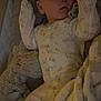 baby, sleeping, pajamas, crib, blanket, stuffed_animal, plush_toy, infant, child, face, soft_lighting, cozy, bedtime, peaceful, cute, indoors, rest, comfort, toddler, nap