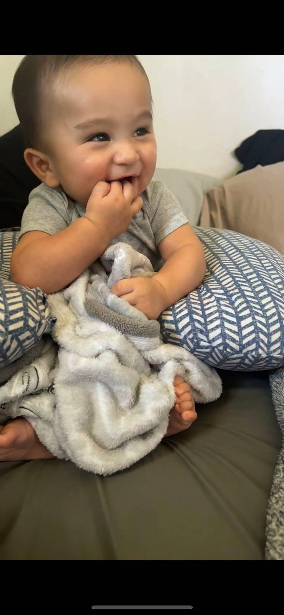 Boston is registered to the contest to win money with this photo: baby, baby_toddler_clothing, cheek, child, comfort, face, finger, gesture, happy, head, linens, nail, pattern, person, room, sitting, skin, sleeve, smile, thumb